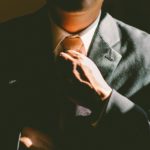 man in suit adjusting tie